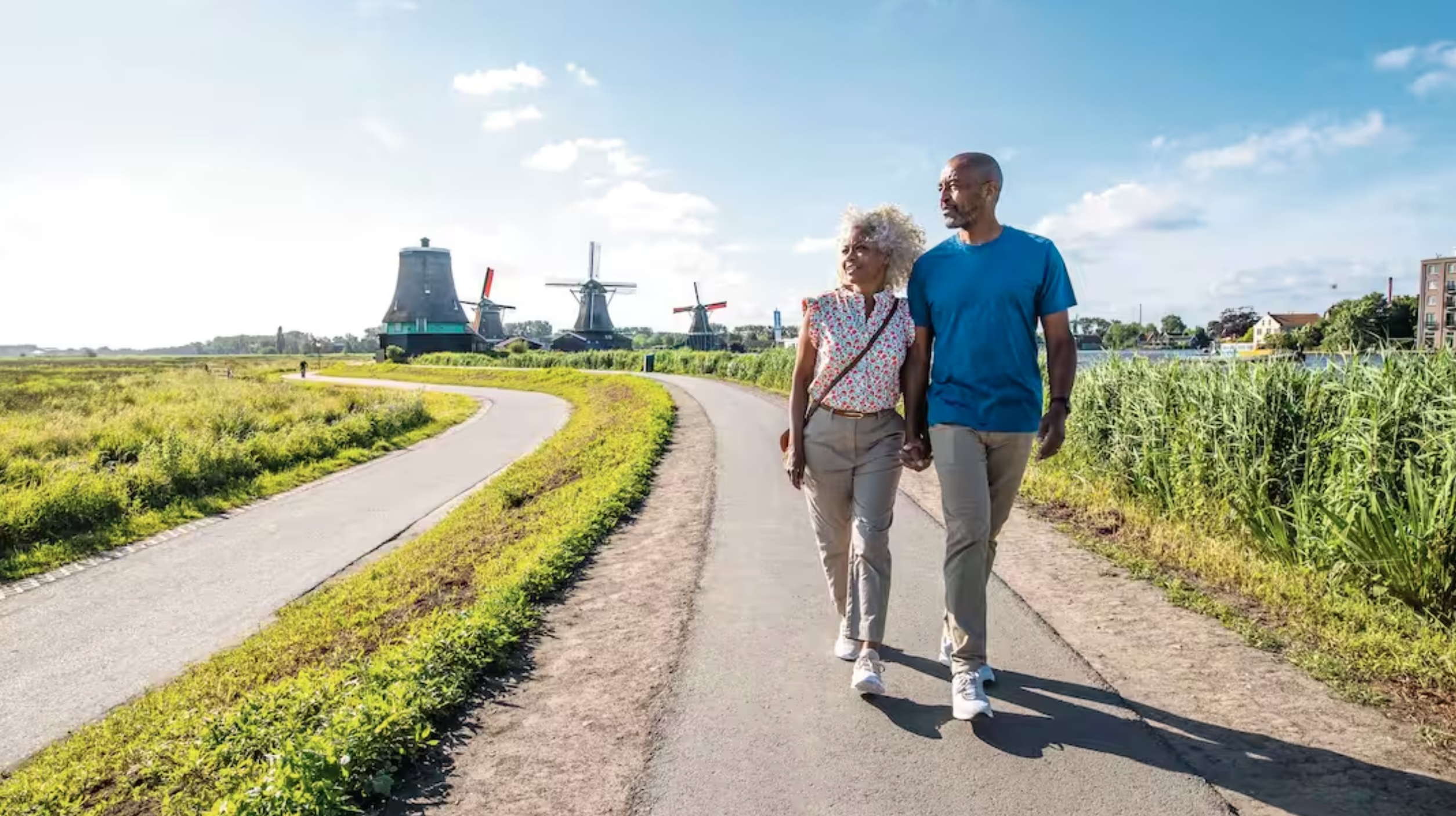 Couple walking with Windmills in the background near Amsterdam
