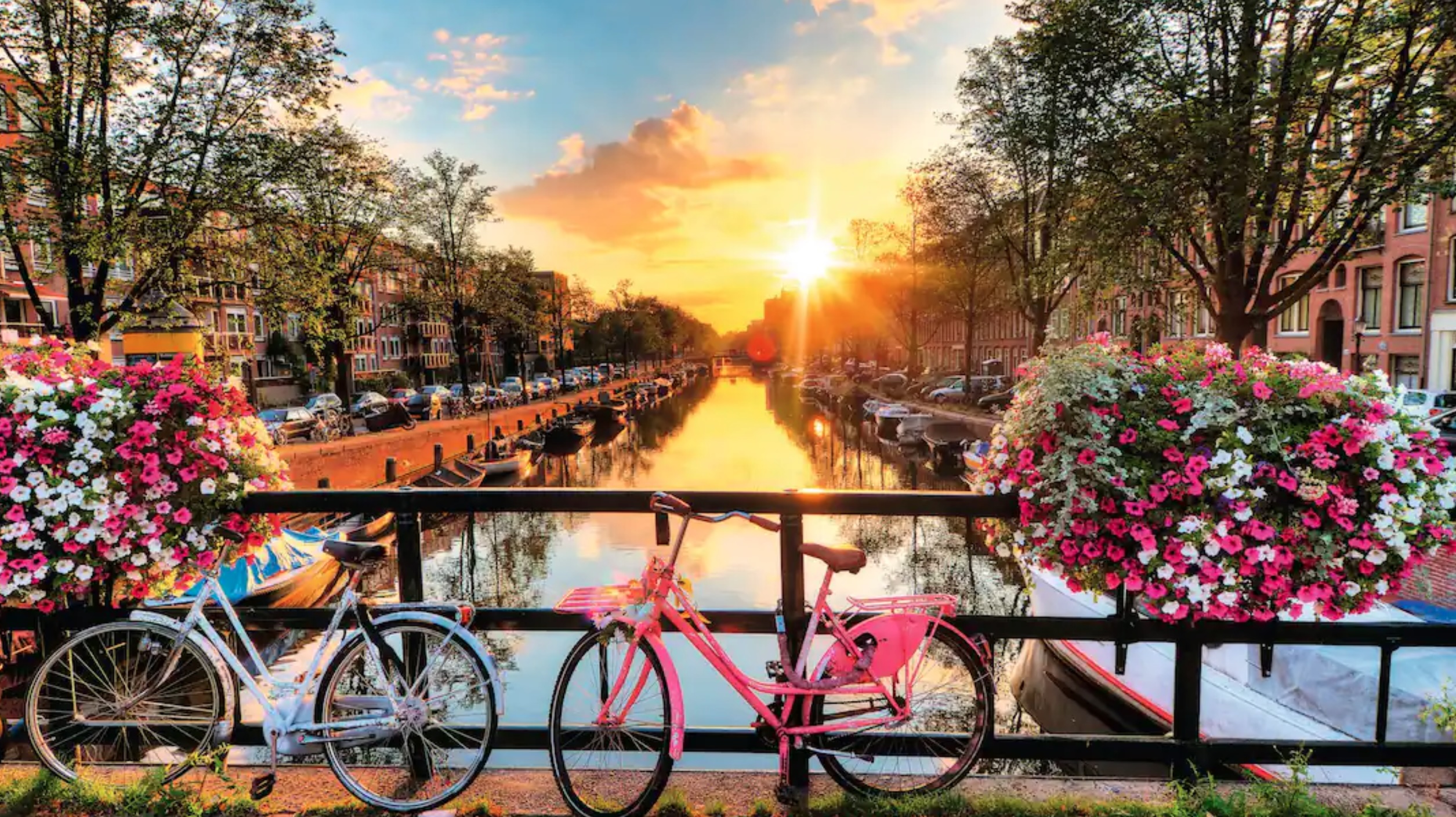sun setting over Amsterdam with cycles on a bridge over the canal in foreground